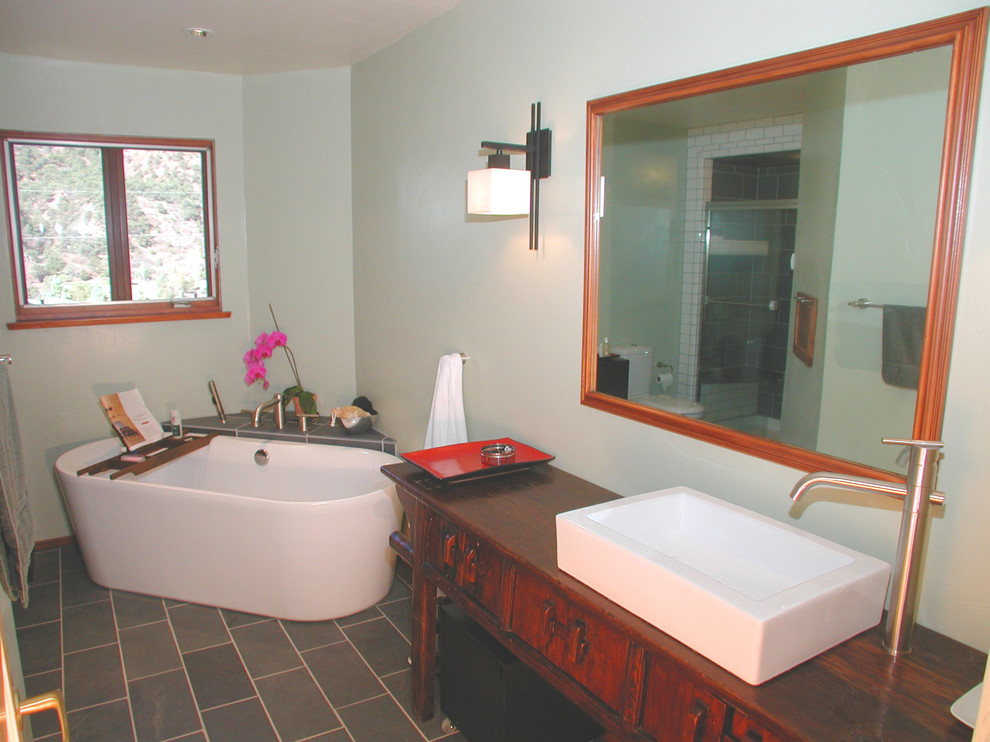 Kleines Modernes Badezimmer En Suite mit grauen Fliesen, Steinfliesen, Aufsatzwaschbecken, dunklen Holzschränken, Waschtisch aus Holz, freistehender Badewanne, grüner Wandfarbe und Schieferboden in Denver
