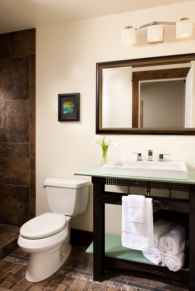 Inspiration för mellanstora moderna en-suite badrum, med en dusch i en alkov, en toalettstol med hel cisternkåpa, brun kakel, ett fristående handfat, bänkskiva i glas och brunt golv