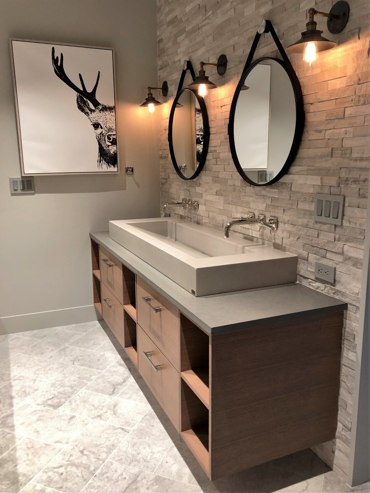 This is an example of a medium sized contemporary bathroom in Denver with flat-panel cabinets, medium wood cabinets, a built-in bath, a two-piece toilet, grey walls, a vessel sink, quartz worktops, grey floors, a hinged door, grey worktops, an alcove shower, grey tiles, stone tiles and marble flooring.