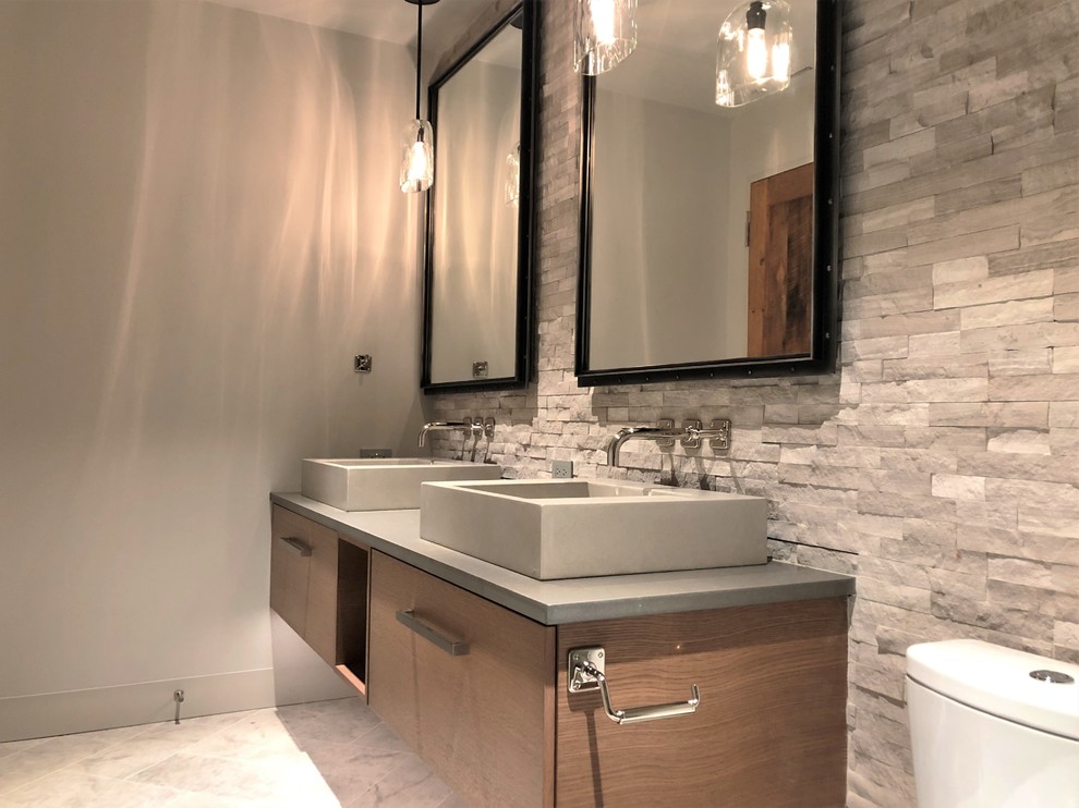 Mid-sized trendy gray tile and stone tile marble floor and gray floor alcove shower photo in Denver with flat-panel cabinets, medium tone wood cabinets, a two-piece toilet, gray walls, a vessel sink, quartzite countertops and gray countertops