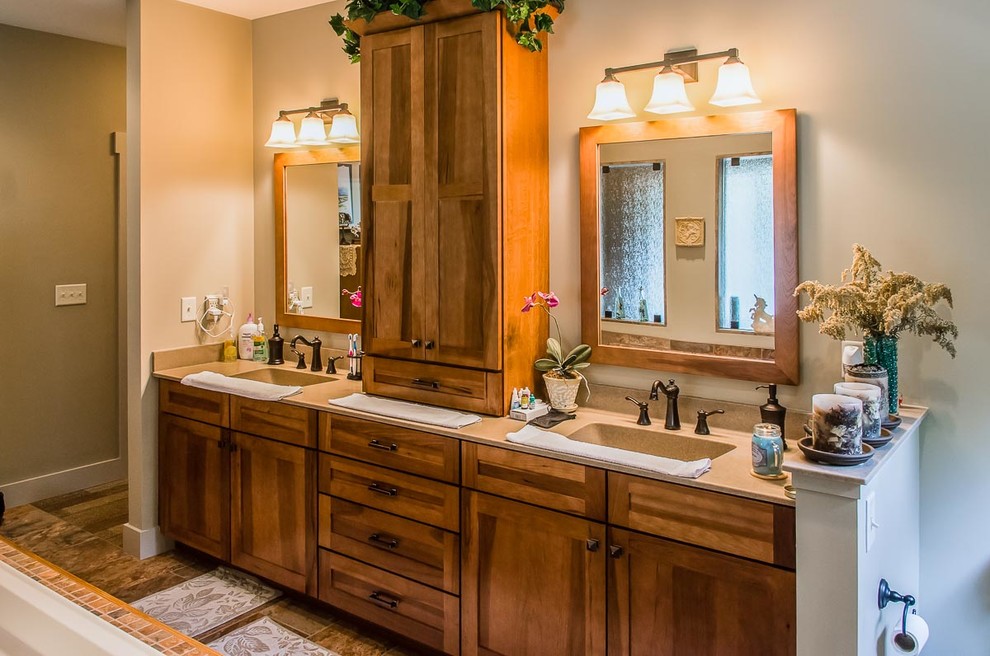 Aménagement d'une grande salle de bain principale craftsman en bois brun avec un placard à porte shaker, un mur beige, un plan de toilette en surface solide, un carrelage beige, un sol en bois brun, un lavabo intégré, un sol marron et un plan de toilette beige.