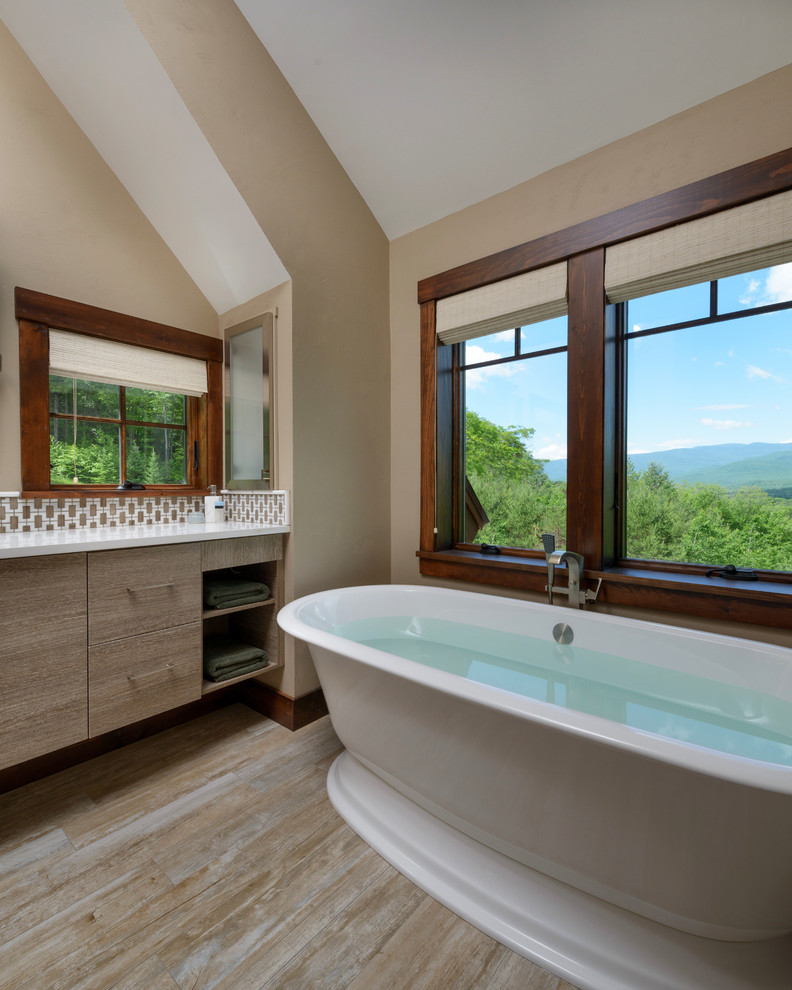 Cette photo montre une salle de bain principale chic en bois clair avec un placard à porte plane, des carreaux de béton, un plan de toilette en quartz modifié, une baignoire indépendante, un mur beige et parquet clair.