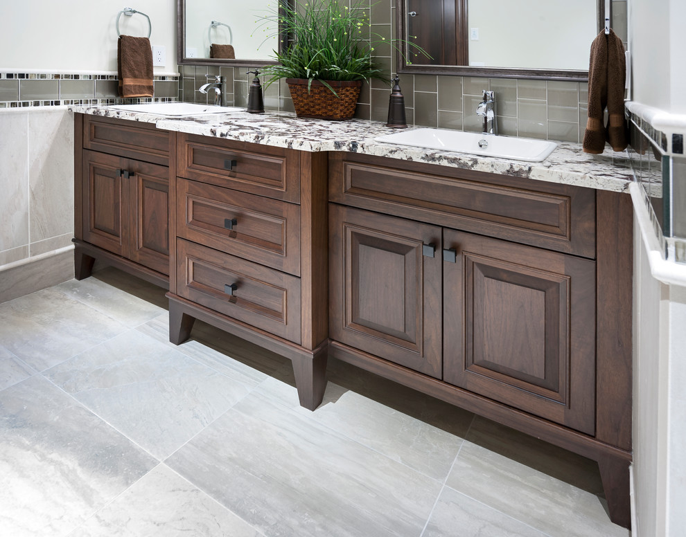 Mid-sized mountain style 3/4 glass tile porcelain tile and multicolored floor bathroom photo in Calgary with raised-panel cabinets, brown cabinets, beige walls and granite countertops