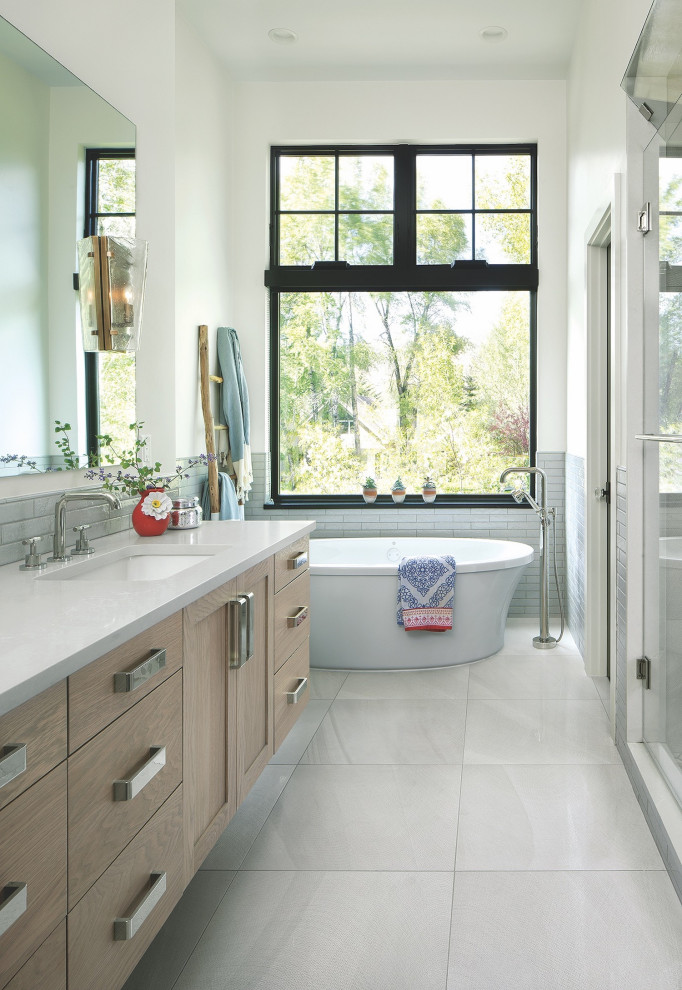This is an example of a farmhouse ensuite bathroom in Denver with flat-panel cabinets, light wood cabinets, a freestanding bath, a walk-in shower, white tiles, ceramic tiles, white walls, porcelain flooring, a submerged sink, white floors, a hinged door, white worktops, a single sink and a floating vanity unit.