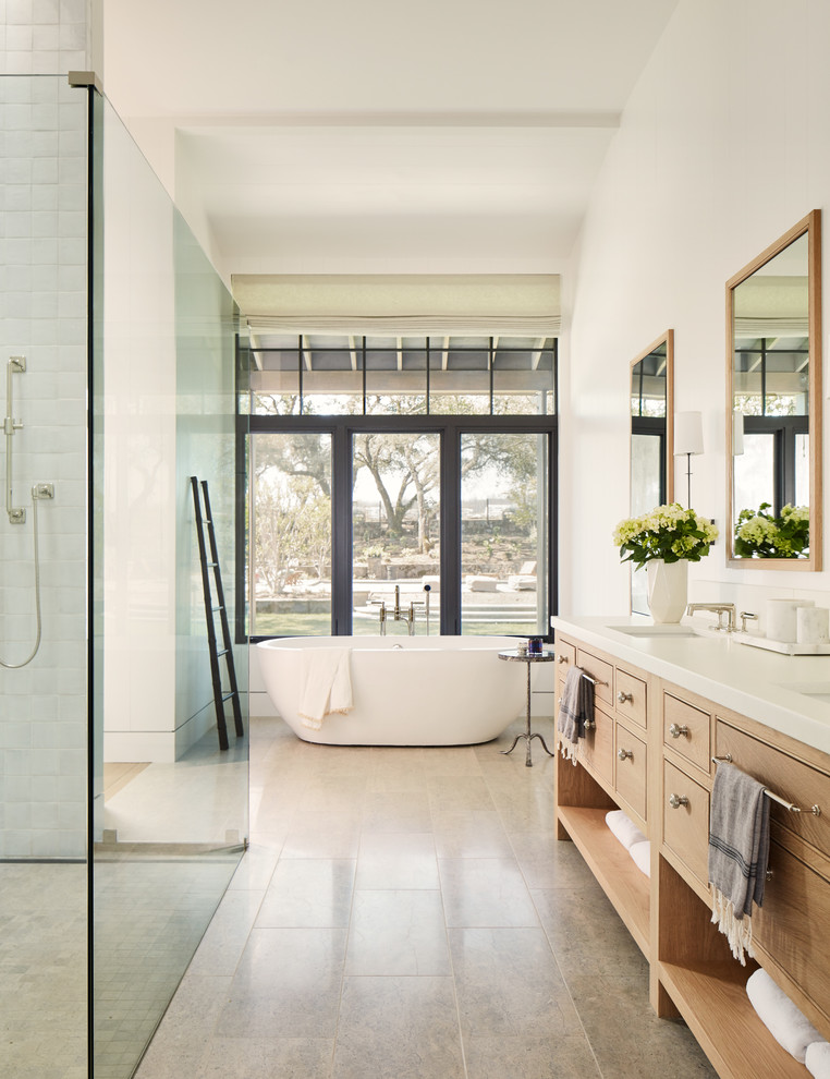 Идея дизайна: ванная комната в стиле кантри с фасадами с декоративным кантом, фасадами цвета дерева среднего тона, отдельно стоящей ванной, белыми стенами, врезной раковиной, серым полом и белой столешницей
