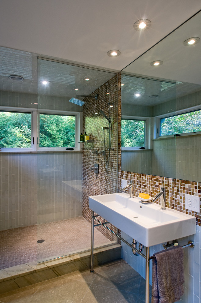 This is an example of a large contemporary ensuite bathroom in Boston with a wall-mounted sink, an alcove shower, brown tiles, beige tiles, multi-coloured tiles, mosaic tiles, grey walls, ceramic flooring, open cabinets, a two-piece toilet, beige floors and a hinged door.