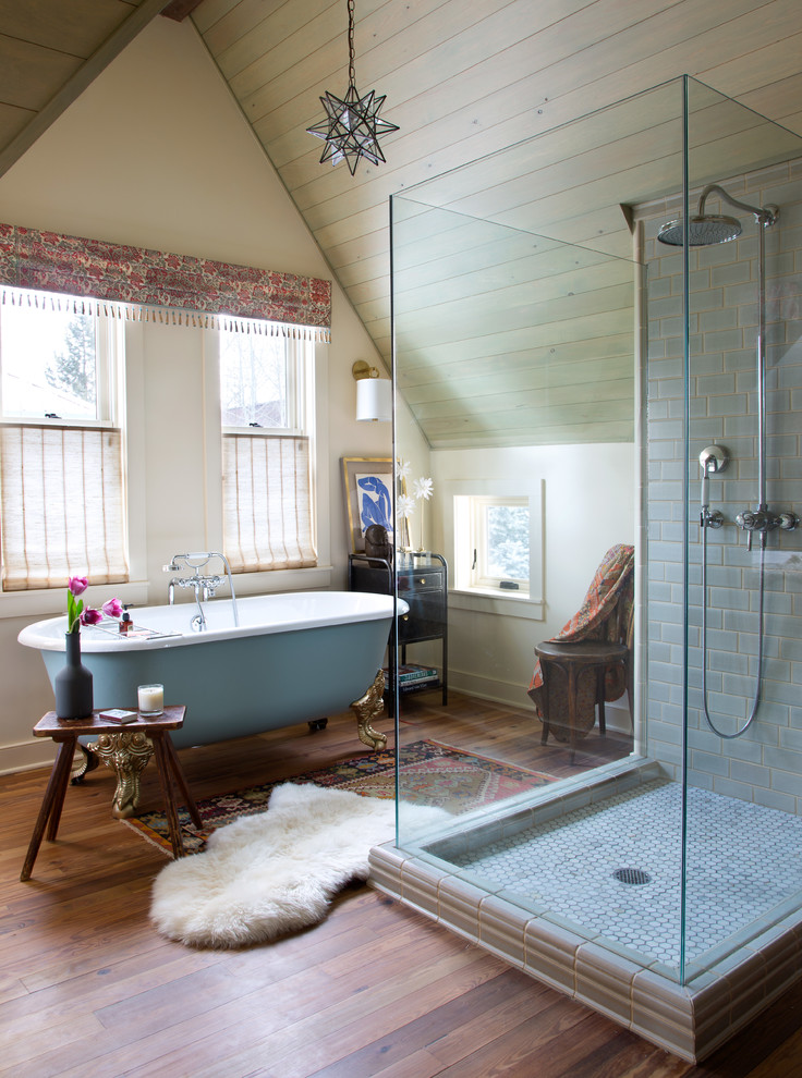 Eklektisches Badezimmer mit Löwenfuß-Badewanne, Eckdusche, grauen Fliesen, beiger Wandfarbe und braunem Holzboden in Denver
