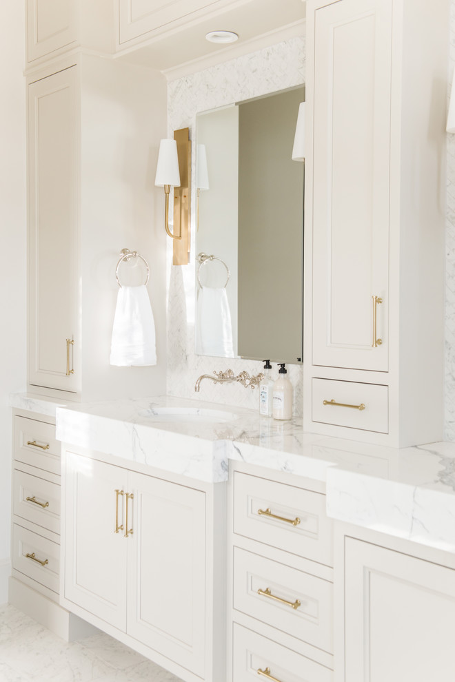 Foto di una stanza da bagno padronale classica di medie dimensioni con ante con riquadro incassato, ante beige, piastrelle bianche, piastrelle di marmo, pareti bianche, pavimento in marmo, lavabo integrato, top in marmo, pavimento bianco e top bianco