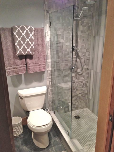 Foto di una piccola stanza da bagno chic con lavabo da incasso, doccia aperta, WC monopezzo, nessun'anta, ante in legno chiaro, top in granito, piastrelle grigie, pareti grigie e pavimento in laminato