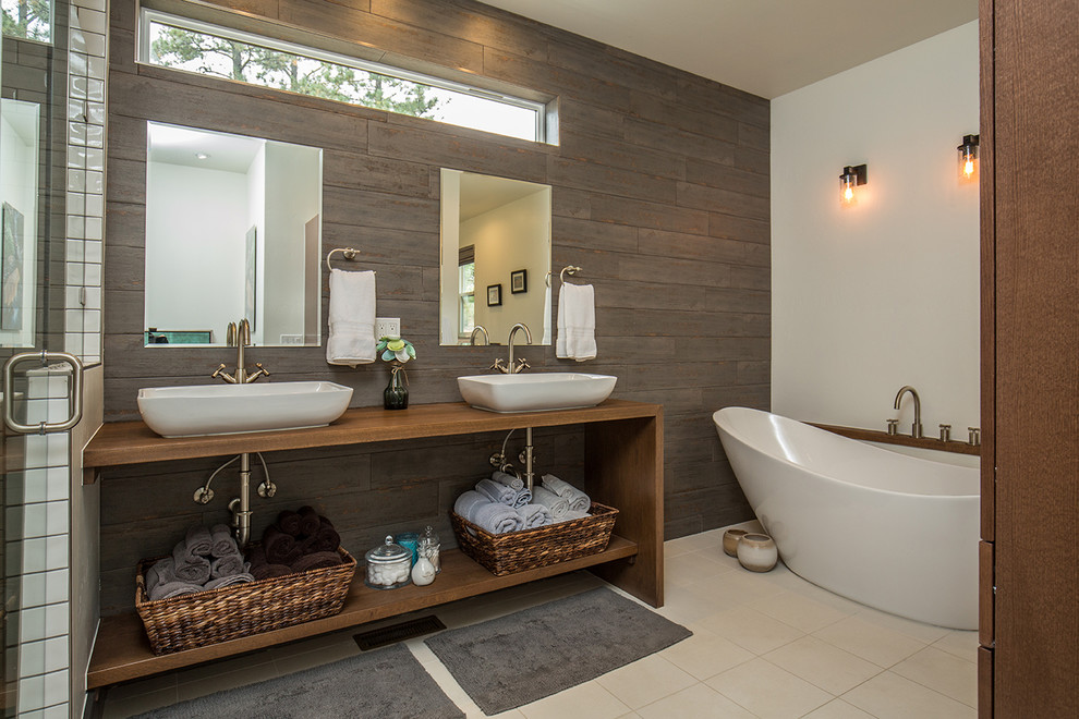 Inspiration for a contemporary bathroom in Albuquerque with medium wood cabinets, a freestanding bath, brown tiles, white walls, a vessel sink, wooden worktops, beige floors and brown worktops.