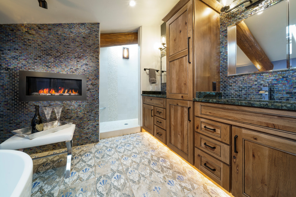 Bathroom - mid-sized rustic master blue tile and glass tile ceramic tile, blue floor, double-sink and exposed beam bathroom idea in Denver with raised-panel cabinets, brown cabinets, a wall-mount toilet, blue walls, an undermount sink, granite countertops, blue countertops and a built-in vanity