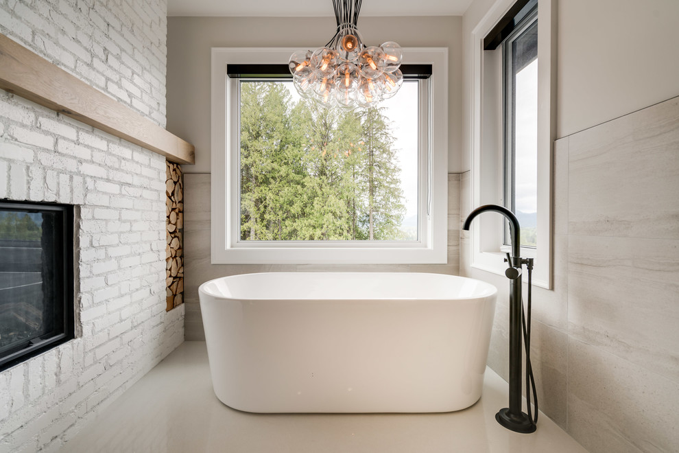 Foto de cuarto de baño actual con bañera exenta, baldosas y/o azulejos grises, paredes grises y suelo gris