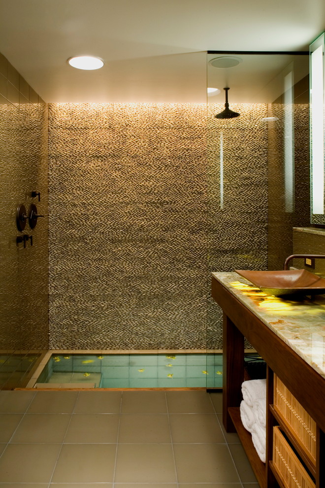 Стильный дизайн: ванная комната в стиле рустика с стеклянной плиткой, столешницей из оникса, настольной раковиной, душем над ванной и бежевыми стенами - последний тренд