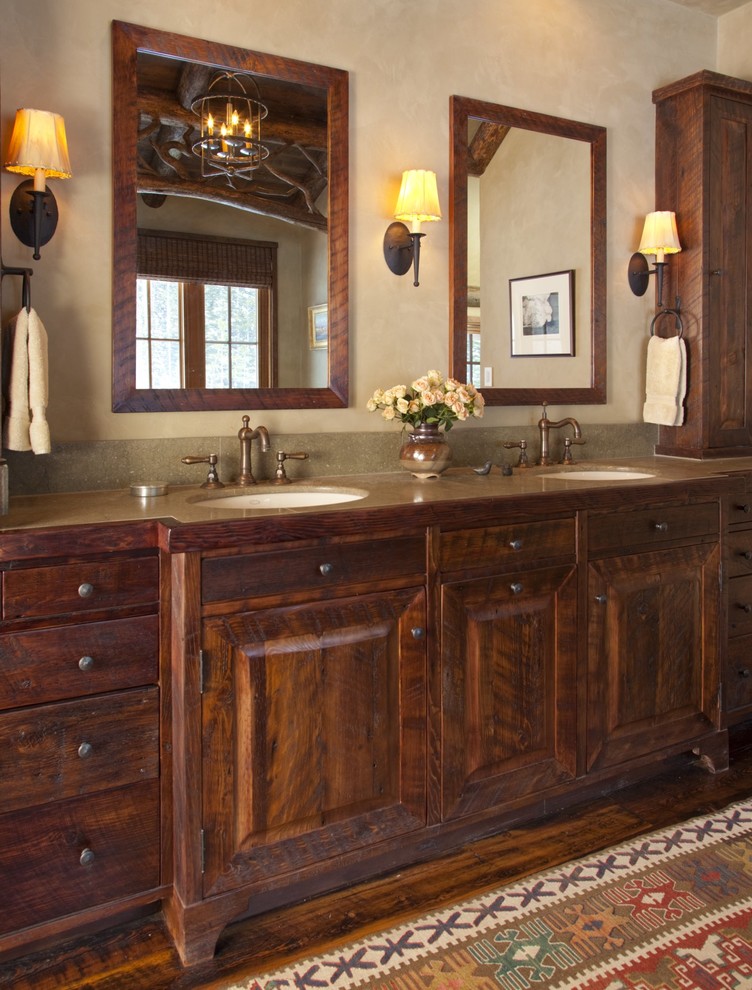 Exemple d'une salle de bain principale montagne en bois foncé de taille moyenne avec un lavabo encastré, un placard avec porte à panneau surélevé, un plan de toilette en granite, un mur beige et un sol en bois brun.