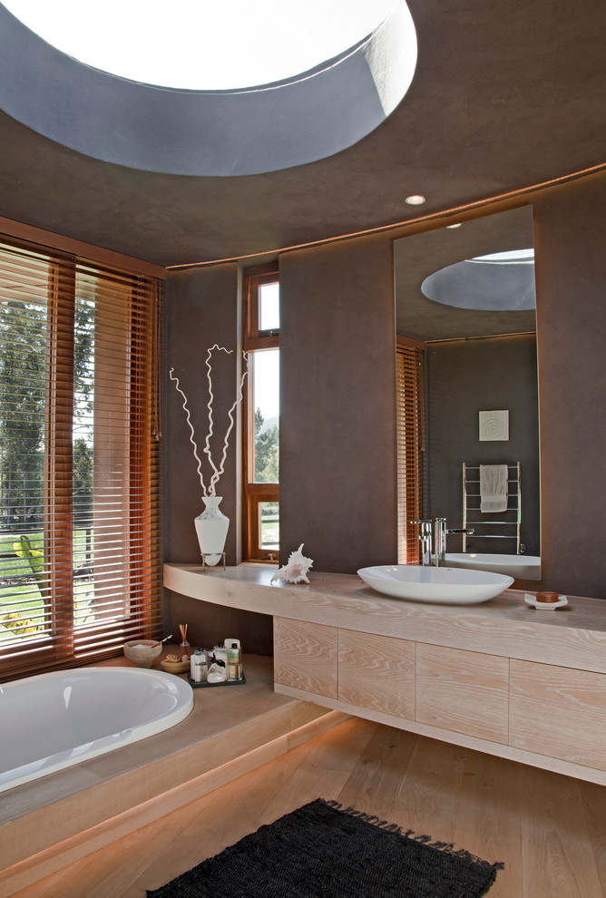 Exempel på ett modernt badrum, med ett fristående handfat, släta luckor, skåp i ljust trä, träbänkskiva och ett platsbyggt badkar