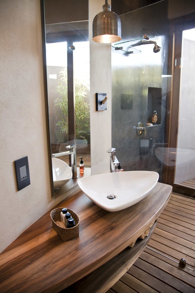 Modelo de cuarto de baño contemporáneo con lavabo sobreencimera, armarios abiertos, encimera de madera y ducha abierta