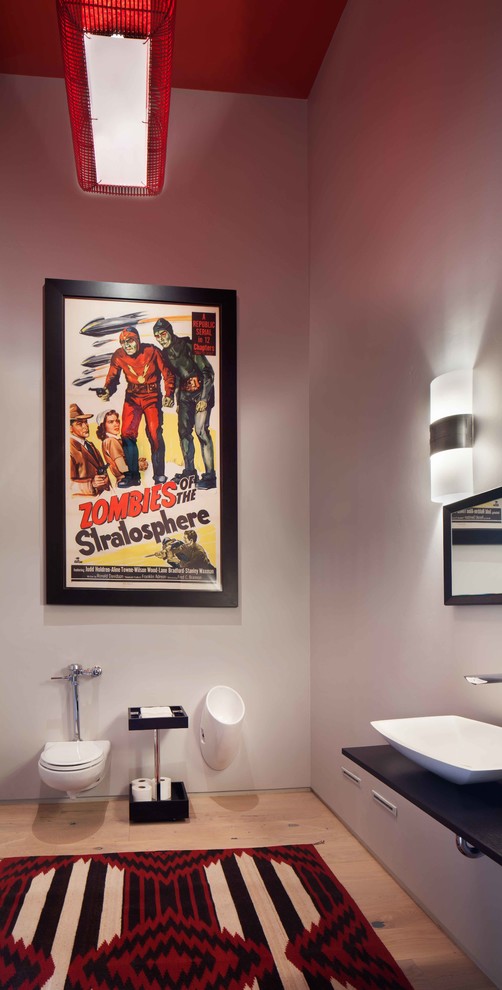 Inredning av ett modernt stort en-suite badrum, med ett fristående handfat, bänkskiva i onyx, en vägghängd toalettstol, grå väggar och ljust trägolv