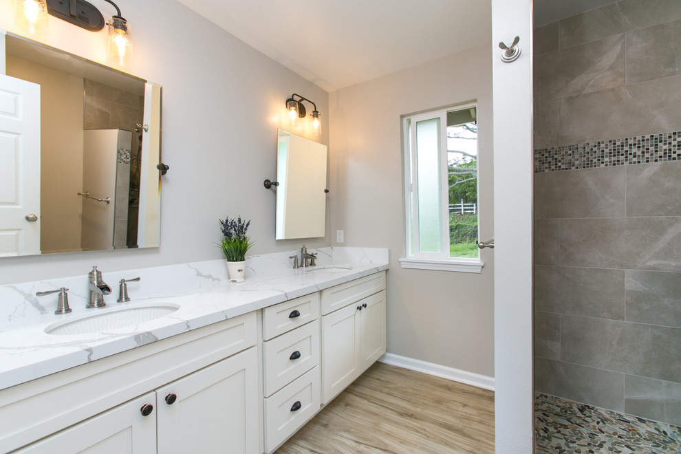 Large classic ensuite bathroom in Hawaii with shaker cabinets, white cabinets, an alcove shower, brown tiles, porcelain tiles, beige walls, a submerged sink, marble worktops, an open shower, light hardwood flooring and beige floors.