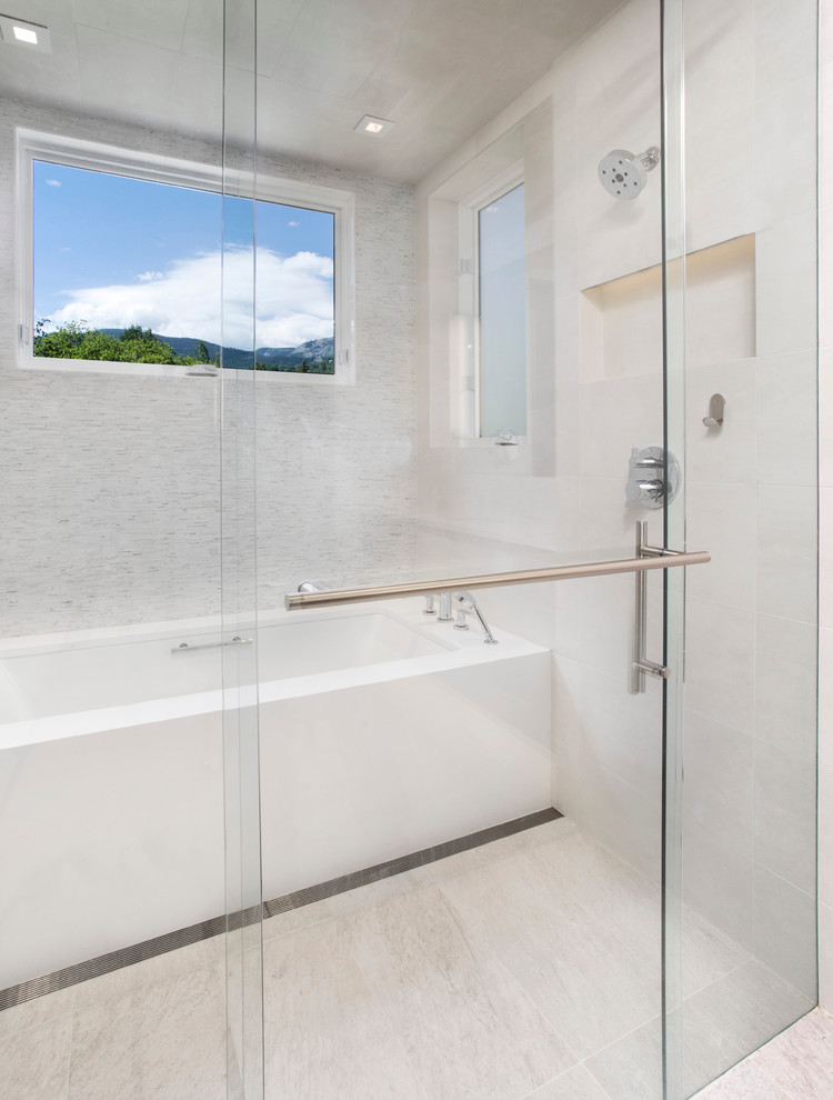 Modern inredning av ett stort en-suite badrum, med ett integrerad handfat, släta luckor, skåp i mellenmörkt trä, bänkskiva i akrylsten, en jacuzzi, en kantlös dusch, en toalettstol med separat cisternkåpa, vit kakel, stickkakel och vita väggar