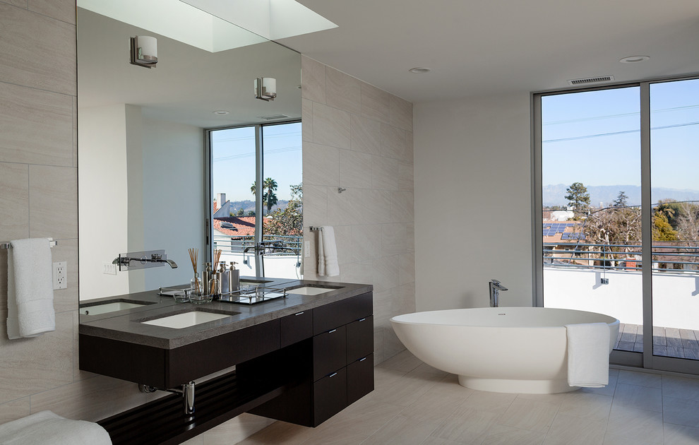 Example of a large trendy master beige tile porcelain tile and gray floor freestanding bathtub design in Los Angeles with an undermount sink, flat-panel cabinets, black cabinets and gray walls