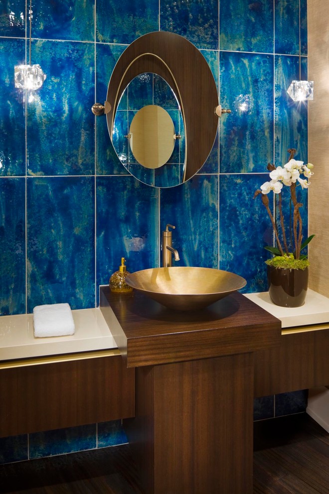 Inspiration pour une salle de bain design en bois foncé avec une vasque, un placard à porte plane, un carrelage bleu, parquet foncé et un carrelage en pâte de verre.