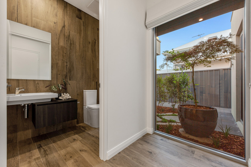 Cette image montre une grande salle de bain principale design en bois foncé avec un placard à porte plane, WC à poser, un mur blanc, un lavabo suspendu, un sol beige et un plan de toilette marron.