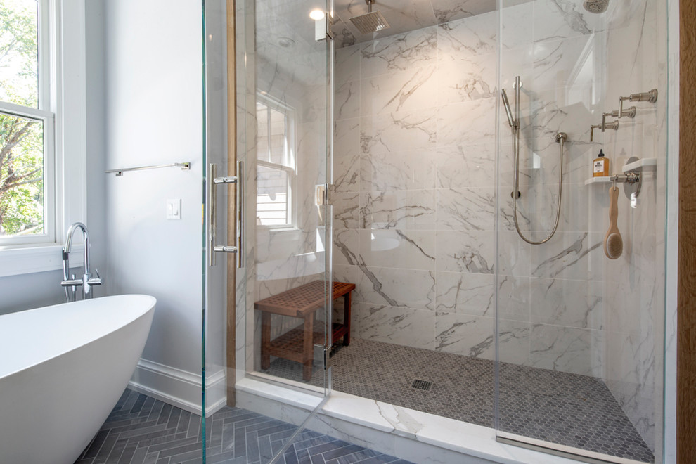 Example of a large minimalist master marble floor and gray floor freestanding bathtub design in New York with medium tone wood cabinets, a one-piece toilet, gray walls, marble countertops, a hinged shower door and white countertops