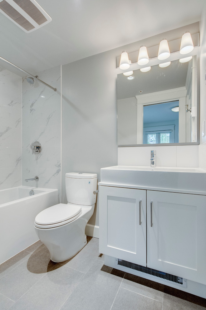 Klassisk inredning av ett mellanstort badrum med dusch, med skåp i shakerstil, vita skåp, ett platsbyggt badkar, en dusch/badkar-kombination, en toalettstol med separat cisternkåpa, vit kakel, keramikplattor, vita väggar, skiffergolv och ett avlångt handfat