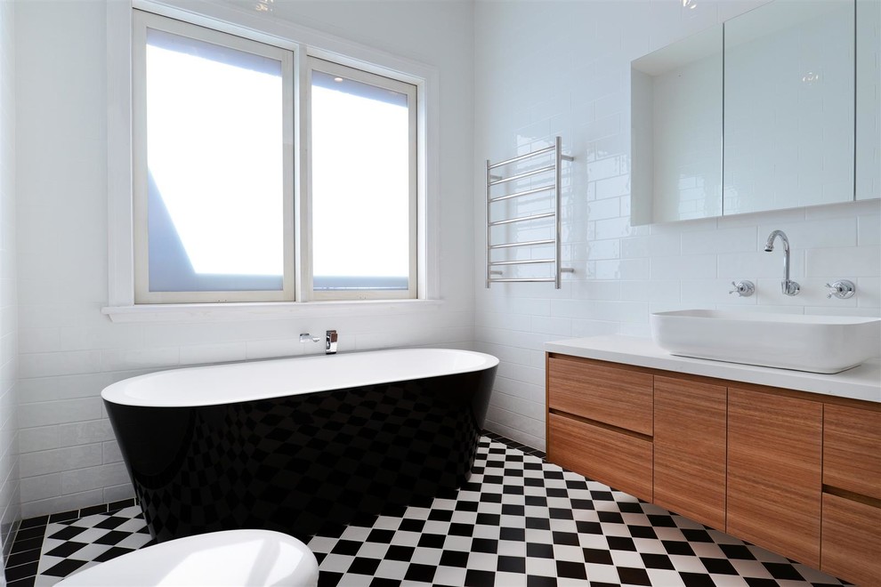 Exempel på ett mellanstort klassiskt badrum med dusch, med släta luckor, skåp i ljust trä, ett fristående badkar, en öppen dusch, en toalettstol med hel cisternkåpa, vit kakel, keramikplattor, vita väggar, klinkergolv i keramik, ett fristående handfat, bänkskiva i akrylsten, flerfärgat golv och med dusch som är öppen