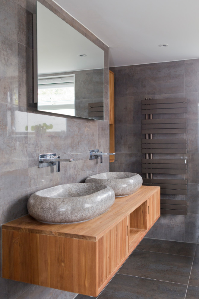 Réalisation d'une salle de bain design en bois brun avec un placard à porte plane, un carrelage gris, une vasque, un plan de toilette en bois, un sol gris, meuble double vasque et meuble-lavabo suspendu.