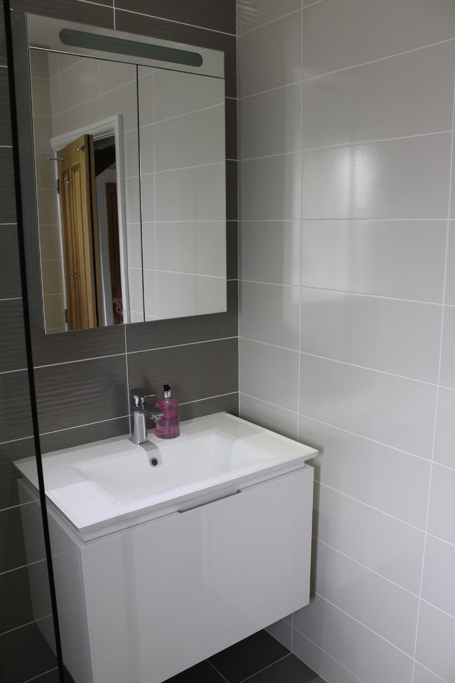エセックスにある高級な小さなコンテンポラリースタイルのおしゃれな浴室 (壁付け型シンク、壁掛け式トイレ、グレーのタイル、磁器タイル) の写真