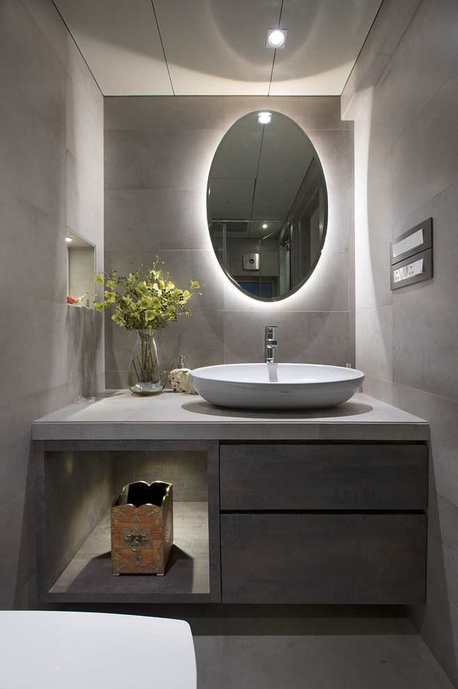 Idée de décoration pour une salle de bain design avec un placard à porte plane, des portes de placard grises, un carrelage gris, un mur gris, sol en béton ciré, une vasque, un sol gris et un plan de toilette gris.