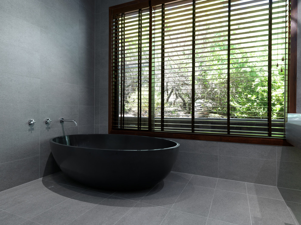 Ejemplo de cuarto de baño principal actual grande con lavabo sobreencimera, encimera de granito, bañera exenta, baldosas y/o azulejos grises, baldosas y/o azulejos de cemento y paredes grises