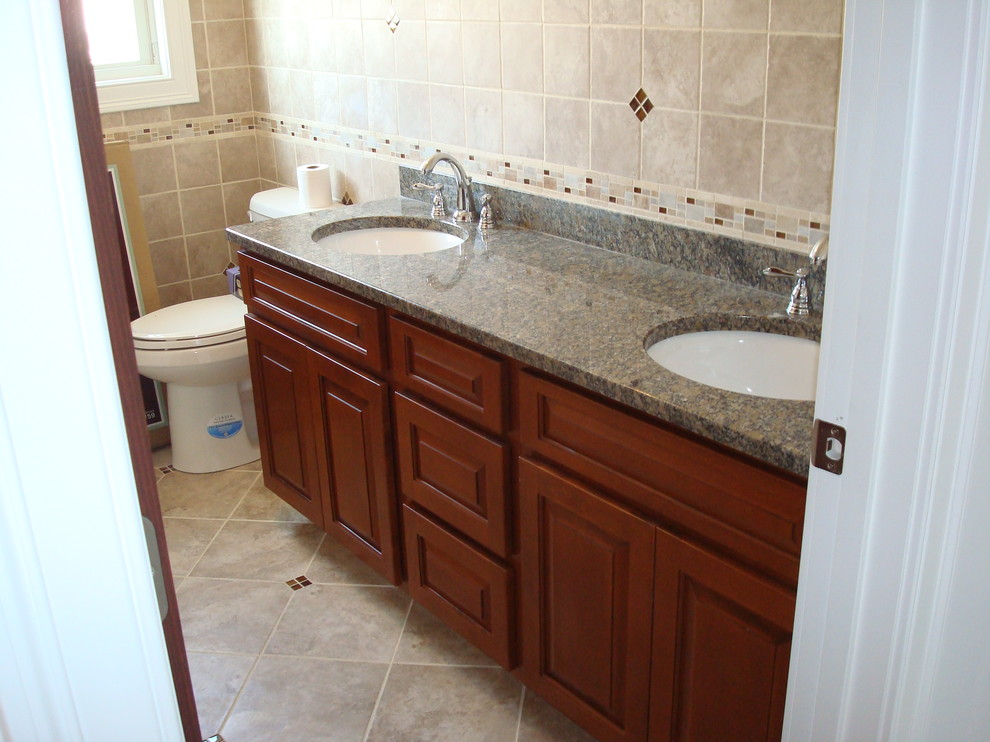Exemple d'une salle de bain tendance en bois foncé avec un placard avec porte à panneau surélevé, un lavabo encastré et un plan de toilette en granite.