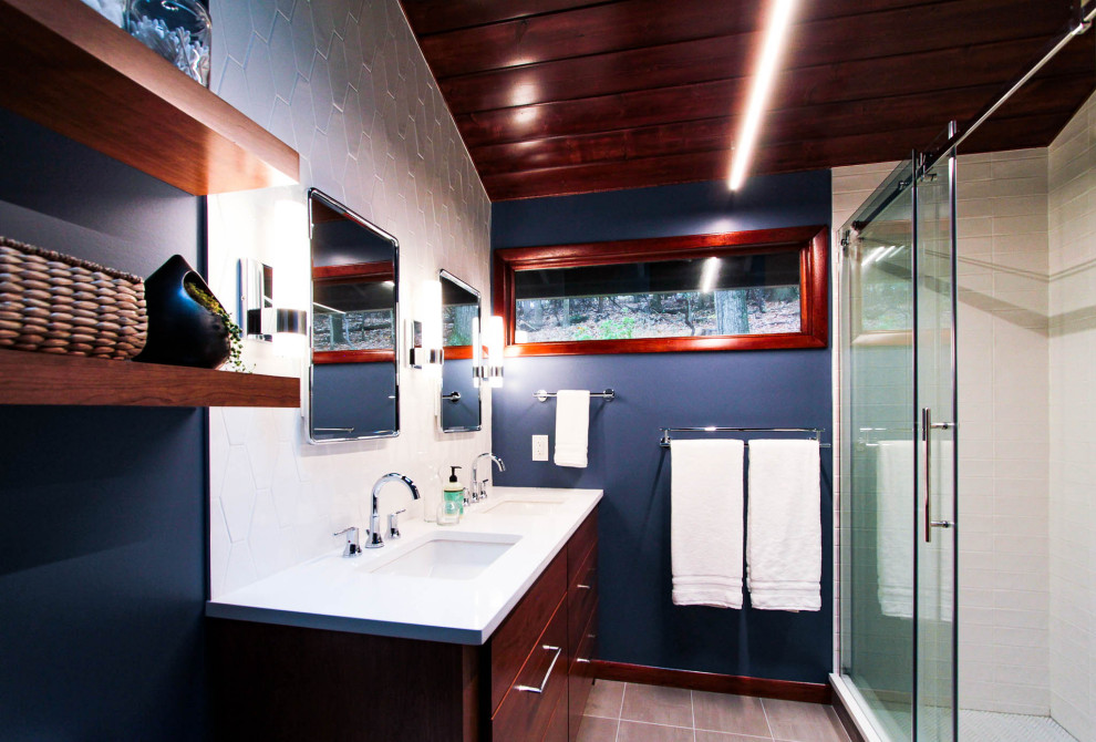 This is an example of a medium sized modern shower room bathroom in Philadelphia with flat-panel cabinets, brown cabinets, an alcove shower, a two-piece toilet, white tiles, ceramic tiles, blue walls, ceramic flooring, a submerged sink, engineered stone worktops, grey floors, a sliding door and white worktops.