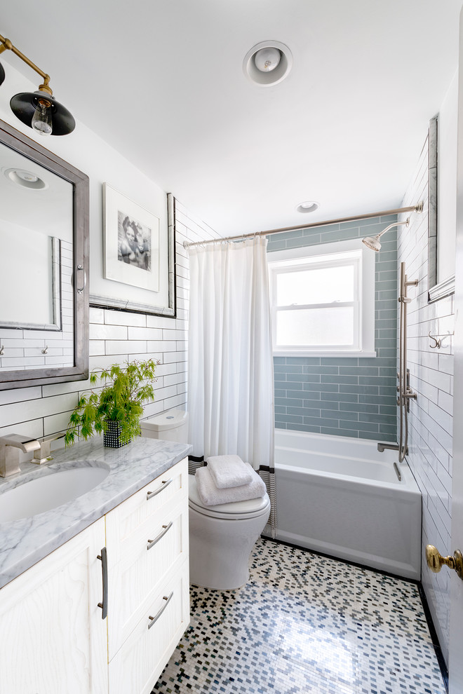 Inredning av ett klassiskt grå grått badrum, med ett undermonterad handfat, vita skåp, ett badkar i en alkov, en dusch/badkar-kombination, blå kakel, tunnelbanekakel och mosaikgolv