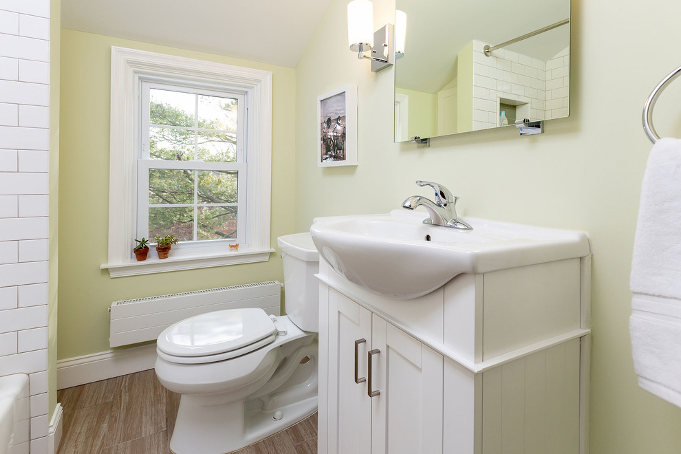 フィラデルフィアにある小さなトランジショナルスタイルのおしゃれなバスルーム (浴槽なし) (シェーカースタイル扉のキャビネット、白いキャビネット、アルコーブ型浴槽、シャワー付き浴槽	、分離型トイレ、白いタイル、サブウェイタイル、黄色い壁、コンソール型シンク、茶色い床、磁器タイルの床、クオーツストーンの洗面台、白い洗面カウンター) の写真