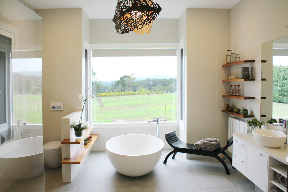 На фото: большая главная ванная комната в современном стиле с белыми фасадами, отдельно стоящей ванной, керамической плиткой и полом из керамической плитки