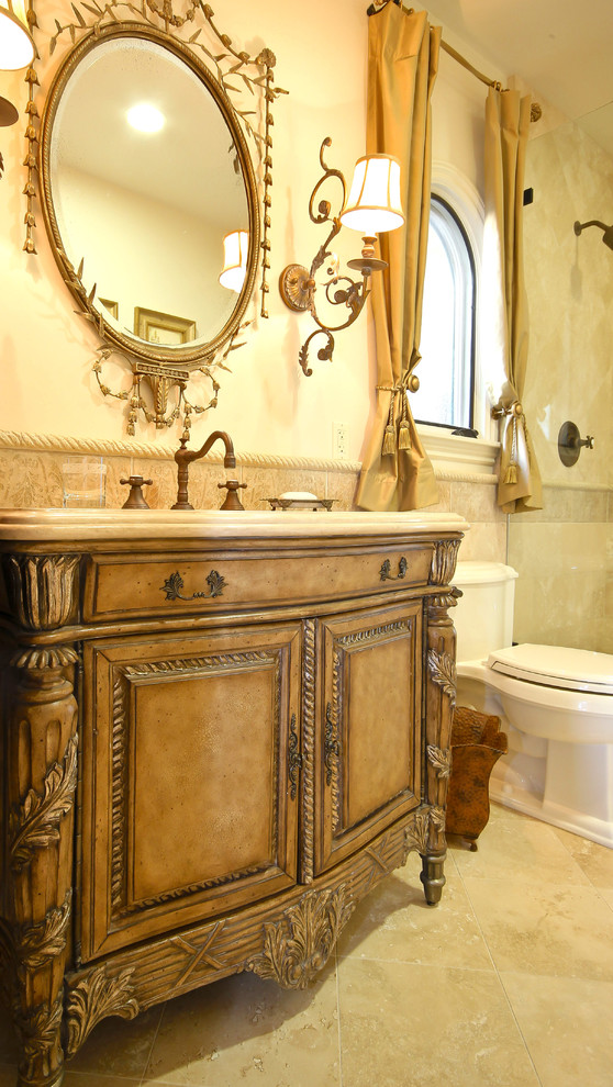 Immagine di una stanza da bagno padronale vittoriana di medie dimensioni con consolle stile comò, ante in legno scuro, doccia ad angolo, WC monopezzo, piastrelle beige, pareti beige e lavabo sottopiano