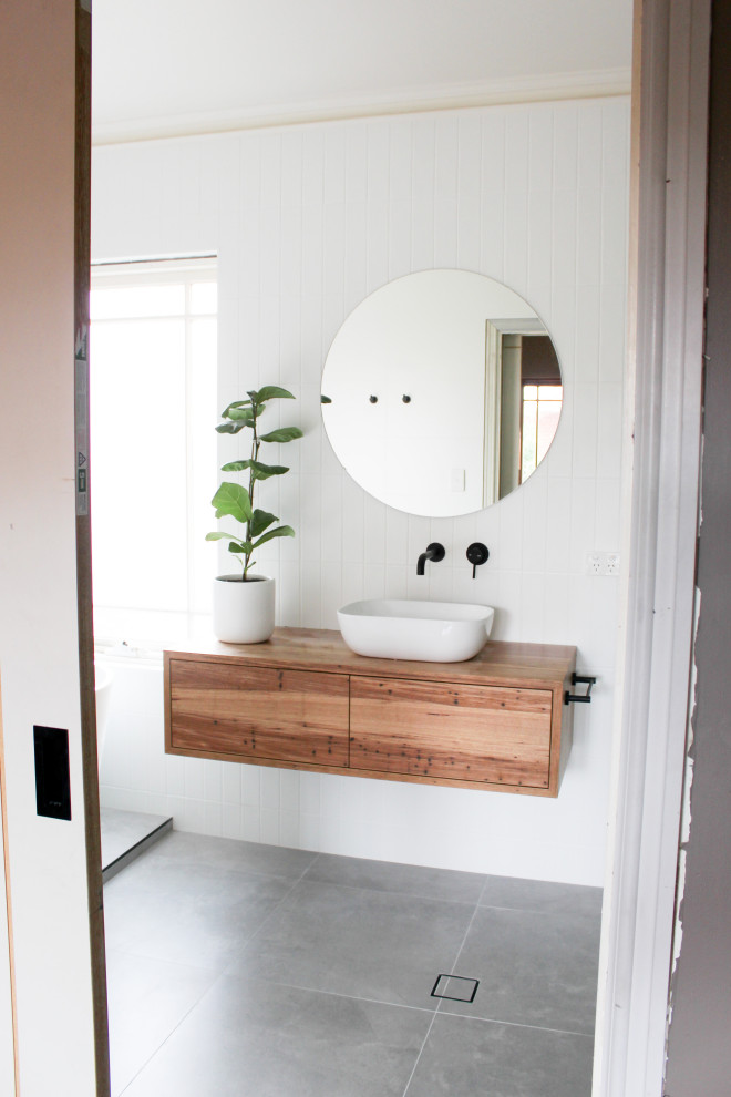Aménagement d'une grande salle de bain principale moderne en bois brun avec un placard en trompe-l'oeil, une baignoire indépendante, une douche d'angle, WC à poser, un carrelage blanc, un carrelage métro, un mur blanc, un sol en carrelage de porcelaine, une vasque, un plan de toilette en bois, un sol gris, une cabine de douche à porte battante, un plan de toilette multicolore, meuble simple vasque et meuble-lavabo suspendu.