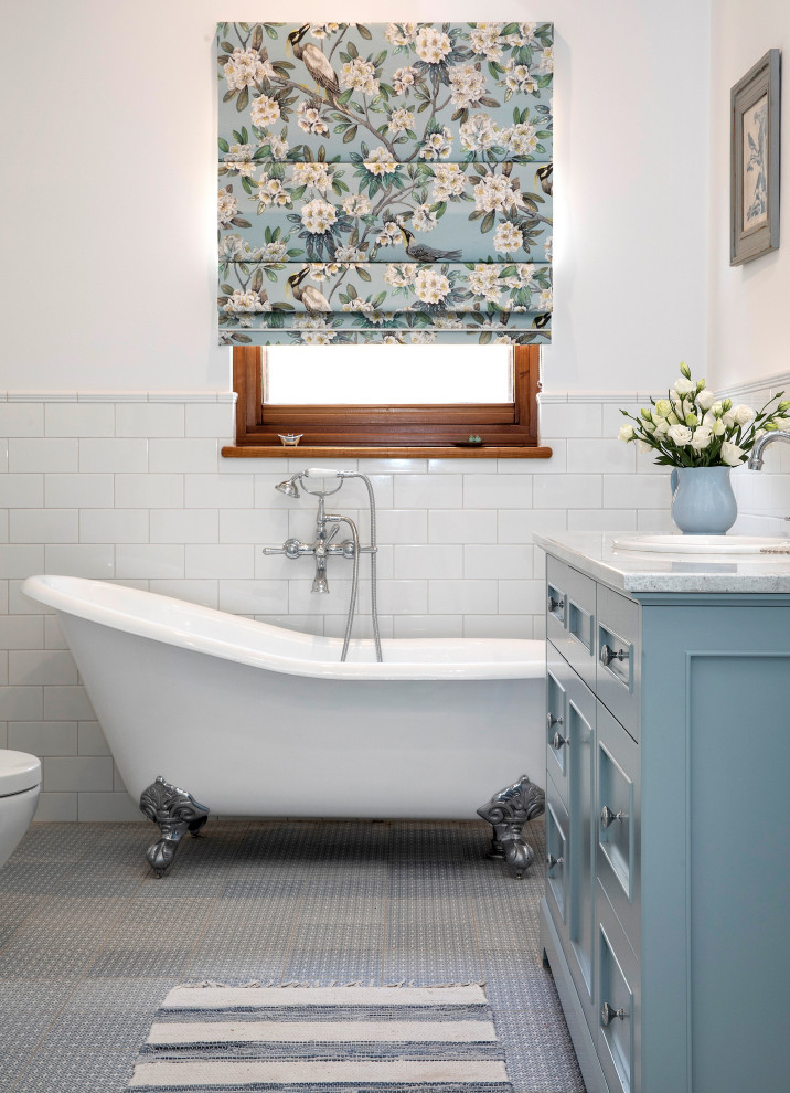 Bild på ett vintage grå grått badrum med dusch, med luckor med infälld panel, blå skåp, ett badkar med tassar, vit kakel, tunnelbanekakel, vita väggar, ett nedsänkt handfat och grått golv