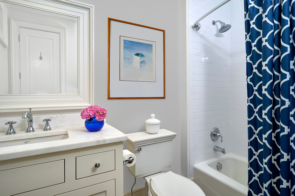 На фото: ванная комната среднего размера в стиле неоклассика (современная классика) с фасадами в стиле шейкер, серыми фасадами, ванной в нише, душем над ванной, унитазом-моноблоком, белой плиткой, плиткой кабанчик, серыми стенами, душевой кабиной, врезной раковиной и мраморной столешницей