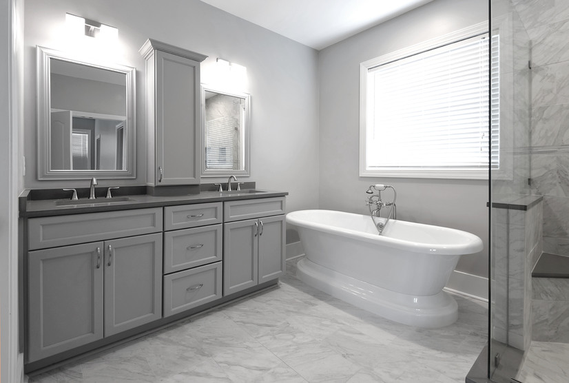 Cette image montre une salle de bain principale design de taille moyenne avec un placard à porte shaker, des portes de placard grises, une baignoire indépendante, une douche d'angle, un carrelage gris, des carreaux de porcelaine, un mur gris, un sol en carrelage de porcelaine, un lavabo encastré, un plan de toilette en quartz modifié, un sol gris, une cabine de douche à porte battante et un plan de toilette gris.