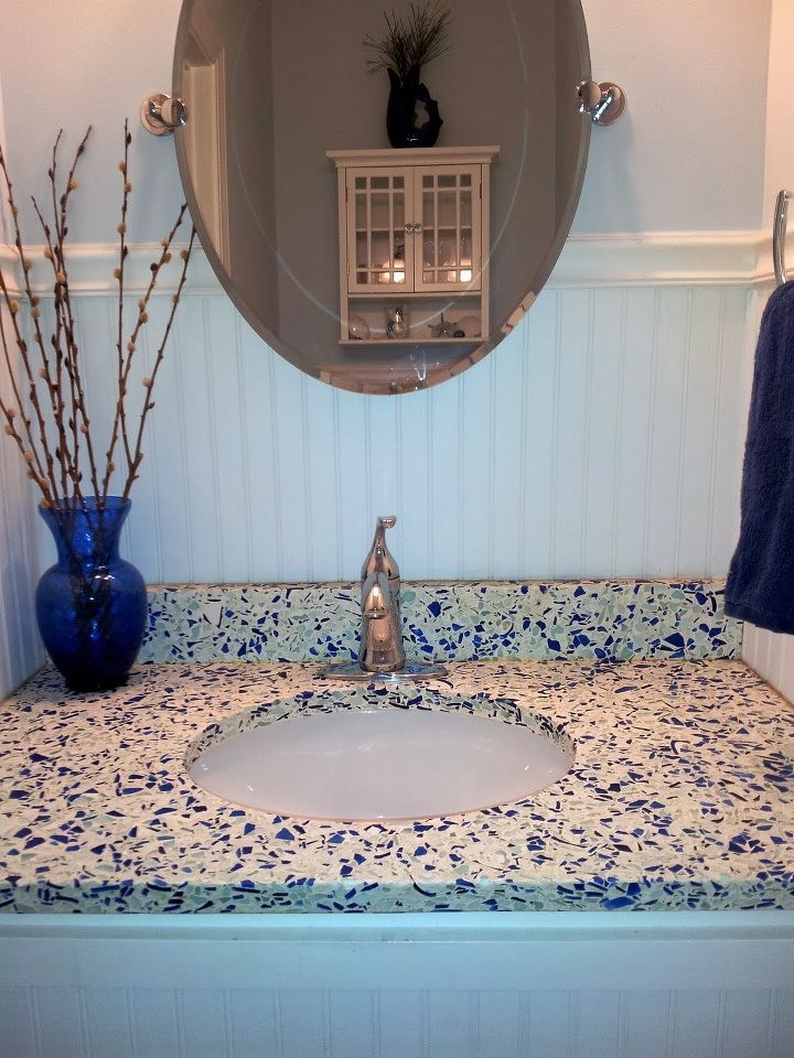 Modelo de cuarto de baño contemporáneo con lavabo bajoencimera, puertas de armario blancas, encimera de vidrio reciclado, bañera empotrada, combinación de ducha y bañera, sanitario de dos piezas y paredes azules