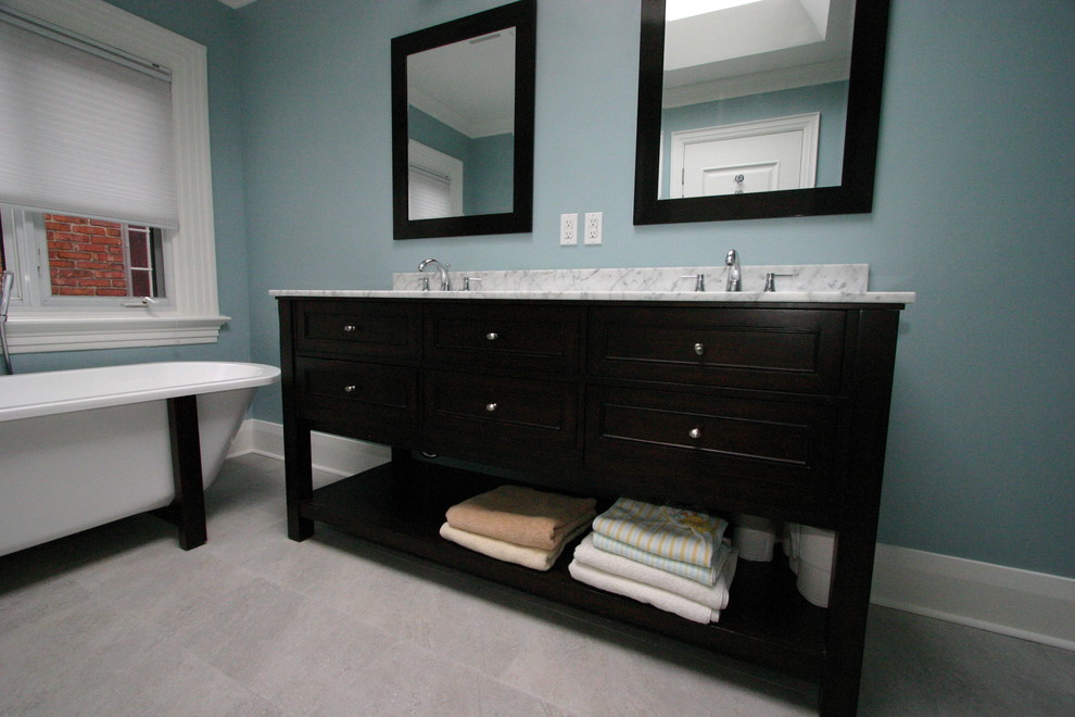 Photo of a modern bathroom in Toronto with freestanding cabinets, dark wood cabinets, a claw-foot bath, a corner shower, a one-piece toilet, blue walls, ceramic flooring, a submerged sink and marble worktops.