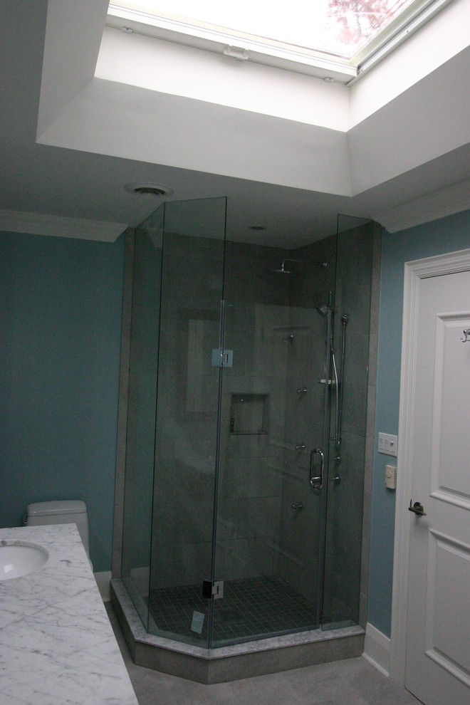 Example of a minimalist ceramic tile bathroom design in Toronto with furniture-like cabinets, dark wood cabinets, a one-piece toilet, blue walls, an undermount sink and marble countertops