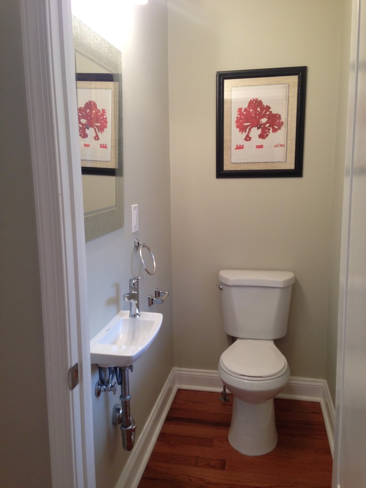 Idéer för ett litet amerikanskt toalett, med ett väggmonterat handfat, en toalettstol med separat cisternkåpa, vita väggar och mellanmörkt trägolv