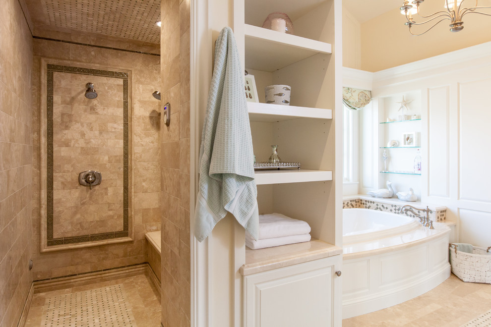 Klassisk inredning av ett mycket stort en-suite badrum, med möbel-liknande, vita skåp, ett platsbyggt badkar, en dubbeldusch, en toalettstol med hel cisternkåpa, beige kakel, travertinkakel, beige väggar, travertin golv, ett undermonterad handfat och marmorbänkskiva
