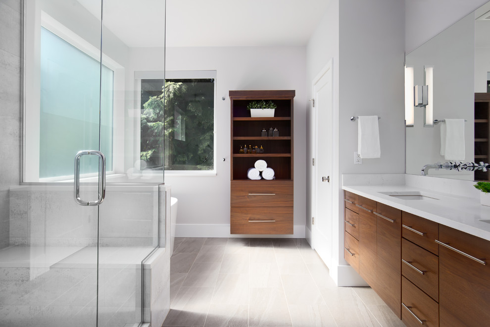 Medium sized contemporary ensuite bathroom in Portland with flat-panel cabinets, medium wood cabinets, a freestanding bath, a walk-in shower, grey tiles, porcelain tiles, white walls, porcelain flooring, a submerged sink, engineered stone worktops, grey floors and a hinged door.
