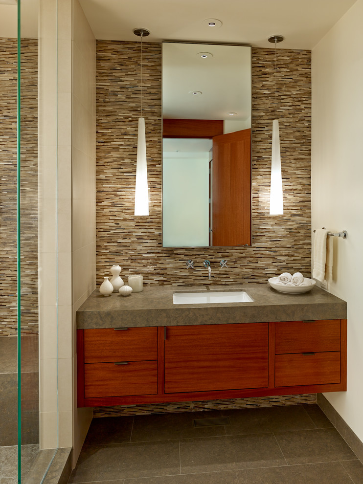 Cette photo montre une salle de bain tendance en bois brun de taille moyenne avec un lavabo encastré, un placard à porte plane, un plan de toilette en calcaire, WC à poser, un carrelage multicolore, un carrelage en pâte de verre, un mur beige et un sol en calcaire.